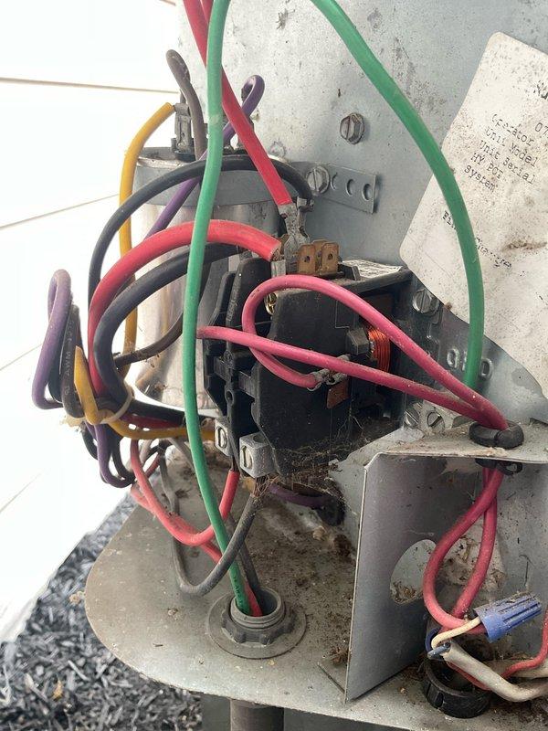 Responded to no-cooling complaint on 16-year-old Goodman central air conditioning system. Upon arrival, confirmed indoor blower operating normally but outdoor condenser fan failed to spin. Compressor attempted to start and hummed but unit overheated and shut down on safety within minutes. Performed diagnostic evaluation of outdoor unit including visual inspection and electrical testing. Confirmed condenser fan motor seized and would not spin even when manually rotated. Tested dual-run capacitor and found failed capacitor unable to provide starting voltage to fan motor. Inspected contactor, wiring connections, and disconnect switch, noting significant corrosion on exterior disconnect box but functional electrical connections. Diagnosed failed condenser fan motor and defective capacitor as root cause of system failure preventing outdoor unit operation and cooling capacity. Documented equipment condition with photos showing outdoor unit configuration, electrical components, and weathered 