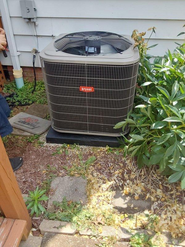 Completed full Bryant HVAC system installation including outdoor condenser unit with protective grille, concrete mounting pad, electrical disconnect box mounted to exterior wall, and indoor evaporator coil. Connected refrigerant lines with brass valve fittings, verified all electrical connections, and integrated system with existing thermostat to provide complete cooling functionality for the residence.