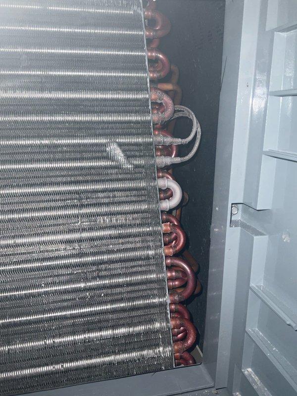 Responded to service call for air conditioning system that was completely iced over and making clanking noises. Upon arrival, found evaporator coil frozen solid with ice buildup preventing proper airflow and refrigerant circulation. Shut down system to allow coil to thaw completely, inspected internal components including finned evaporator assembly and copper refrigerant lines for damage or restrictions. Documented condition of furnace-mounted A-coil and surrounding mechanical connections with photos showing extent of ice formation and equipment configuration.