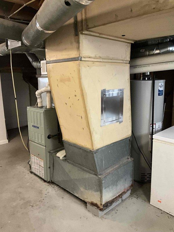 Responded to no cooling complaint and performed system evaluation. Upon inspection, assessed existing furnace and HVAC equipment configuration in basement mechanical room, including custom-built enclosure, ductwork routing, and associated plumbing connections. Documented current equipment condition and provided replacement estimate for new system installation.
