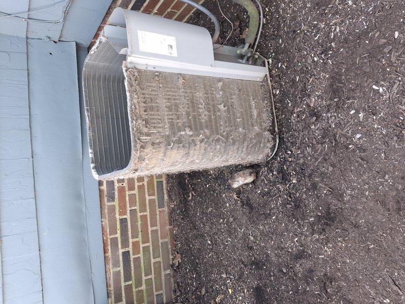 Responded to service call for 12-year-old exterior AC unit with reported compressor noise. Upon arrival, performed visual inspection revealing heavily soiled condenser coils with significant dirt, dust, and debris accumulation on cooling fins and internal components. Opened top panel to assess compressor operation and internal condition. Documented extensive buildup on both exterior surfaces and condenser coil fins, which can restrict airflow and cause abnormal operating sounds. Photographed unit condition showing clogged vertical fins and accumulated particulate matter throughout system. Recommended thorough coil cleaning and system maintenance to restore proper airflow and eliminate noise issue, as debris buildup is likely contributing factor to reported compressor sound.