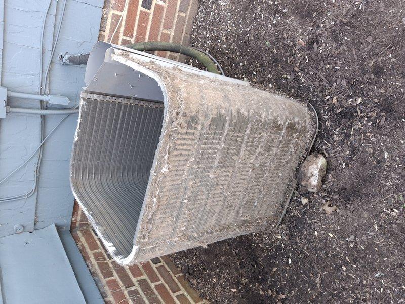 Responded to service call for 12-year-old exterior AC unit with reported compressor noise. Upon arrival, performed visual inspection revealing heavily soiled condenser coils with significant dirt, dust, and debris accumulation on cooling fins and internal components. Opened top panel to assess compressor operation and internal condition. Documented extensive buildup on both exterior surfaces and condenser coil fins, which can restrict airflow and cause abnormal operating sounds. Photographed unit condition showing clogged vertical fins and accumulated particulate matter throughout system. Recommended thorough coil cleaning and system maintenance to restore proper airflow and eliminate noise issue, as debris buildup is likely contributing factor to reported compressor sound.