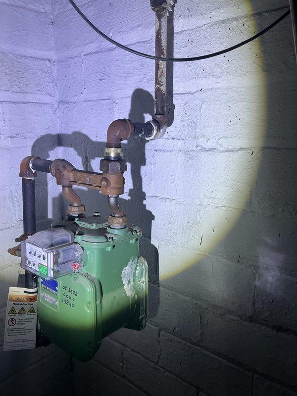 Responded to gas leak reported in basement of century-old home originating from gas fireplace supply line. Upon arrival, conducted comprehensive visual inspection of gas piping system and utilized pressure testing equipment to isolate leak location. Testing revealed compromised connection at gas meter assembly where copper supply lines interface with regulator unit. Performed pressure test on system using calibrated gauge to verify leak and assess system integrity. Tightened affected fittings and connections, then re-tested system to confirm proper gas pressure and verify leak elimination. All connections passed final pressure test with readings within manufacturer specifications. System restored to safe operating condition and confirmed no additional leaks present throughout accessible gas piping network.