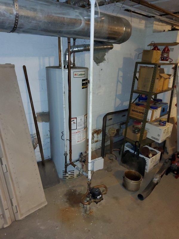 Responded to service call for multiple plumbing issues in 104-year-old residential property, including continuously running toilet in bathroom and sudden loss of cold water pressure at kitchen sink. Upon inspection of basement utility area, evaluated water heater installation, supply line configuration, and overall plumbing system condition. Assessed copper piping, PVC connections, and water distribution system for potential causes of low pressure and leaks mentioned by homeowner. Documented existing conditions including visible water staining on basement walls, aging infrastructure typical of early 1920s construction, and current mechanical system setup. Photographed water heater area and plumbing connections for service records and future reference.