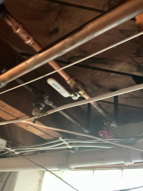 Replaced main water shutoff valve assembly with new brass valve and copper pipe fittings in utility space. Installation included proper connection to existing copper supply line with multiple brass connectors to ensure secure, leak-free operation. Work was completed with assistance to ensure proper shutoff functionality for the home's main water supply system.