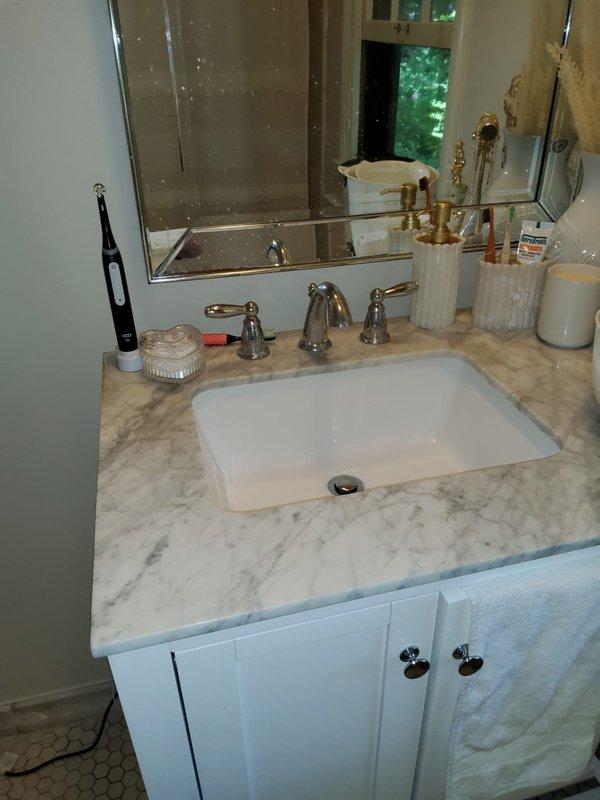 Responded to whole-home drain clog in century-old residence. Inspected plumbing system including bathroom vanity with undermount sink, chrome three-handle faucet, and P-trap assembly beneath cabinet. Cleared blockage in main drainage line to restore proper flow throughout the home. All fixtures tested and confirmed operational upon completion.