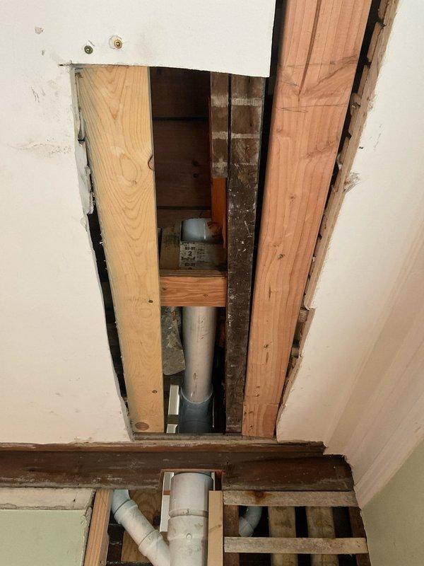Removed toilet and chipped away concrete around flange to access subfloor structure. Installed support boards beneath flange and additional blocking to reinforce bottom side of drain elbow. Reinstalled toilet with new wax ring, secured mounting bolts, and applied silicone bead around base. Performed leak test and operational check, verified no rocking or movement of fixture.