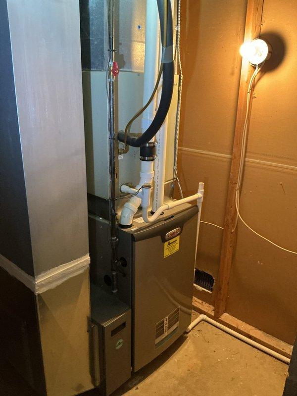Conducted on-site assessment for HVAC system replacement in residential basement utility area. Evaluated existing furnace unit, ductwork configuration, and associated mechanical systems including metal cabinet components, PVC drainage lines, and flexible duct connections. Documented current equipment condition, noting wire connections, conduit routing, and spatial constraints within confined work area. Photographed existing installation to support replacement estimate preparation, capturing furnace positioning, ventilation system layout, and accessibility considerations for future equipment installation.