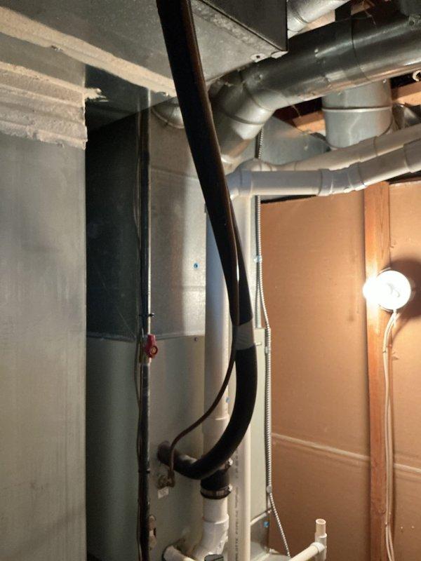 Conducted on-site assessment for HVAC system replacement in residential basement utility area. Evaluated existing furnace unit, ductwork configuration, and associated mechanical systems including metal cabinet components, PVC drainage lines, and flexible duct connections. Documented current equipment condition, noting wire connections, conduit routing, and spatial constraints within confined work area. Photographed existing installation to support replacement estimate preparation, capturing furnace positioning, ventilation system layout, and accessibility considerations for future equipment installation.