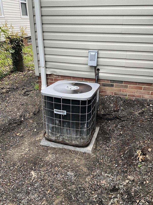Conducted on-site evaluation of 20+ year old residential air conditioning system for replacement estimate. Documented existing outdoor condenser unit showing significant age-related deterioration, including visible rust staining, water damage, and weathering on exterior casing. Unit located in side yard on concrete pad with electrical disconnect box and conduit properly mounted on exterior wall. Assessed installation site conditions, photographed equipment placement area, and confirmed system specifications for replacement proposal.