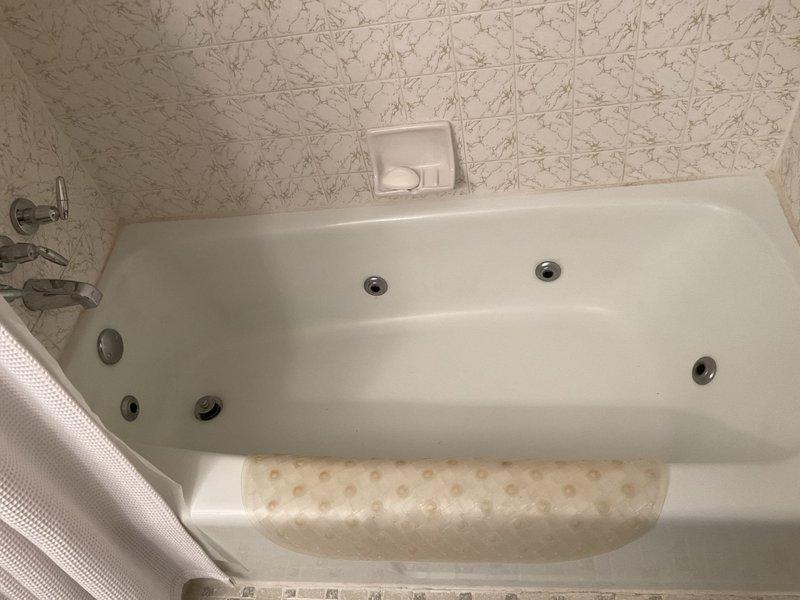 Responded to a report of a small drip from plastic piping associated with a jetted whirlpool bathtub in a 60-year-old residence. Accessed the plumbing system through an existing access panel in an adjacent closet, which provided visibility to the tub's circulation pump, associated piping connections, and related mechanical components. Upon inspection, identified the source of the leak in the plastic supply or return line connected to the jetted tub's pump assembly. Repaired the compromised connection point, verified all jet system plumbing connections for integrity, and tested the whirlpool system for proper operation and complete leak elimination. Confirmed no water intrusion or damage to surrounding flooring or walls in the access area.
