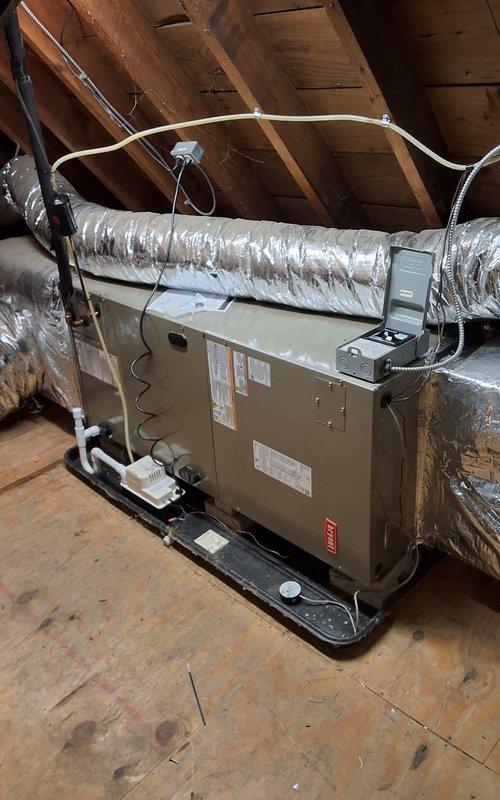 # HVAC Installation Summary

Completed full Bryant air conditioning system installation including outdoor condenser unit mounted on new concrete pad with new electrical disconnect box for safe servicing access. Installed indoor air handler in attic space equipped with new evaporator coil and blower motor, positioned on black drain pan for condensate management. Connected flexible insulated ductwork to air handler and secured to roof structure with proper metal strapping. Installed new condensate pump with PVC drain line routing to prevent water damage. Mounted new programmable thermostat for enhanced temperature control and energy efficiency. All electrical connections completed to code specifications. System startup performed with verification of proper refrigerant charge, airflow measurements, and operational testing of all components. Installation meets manufacturer specifications and local building codes.