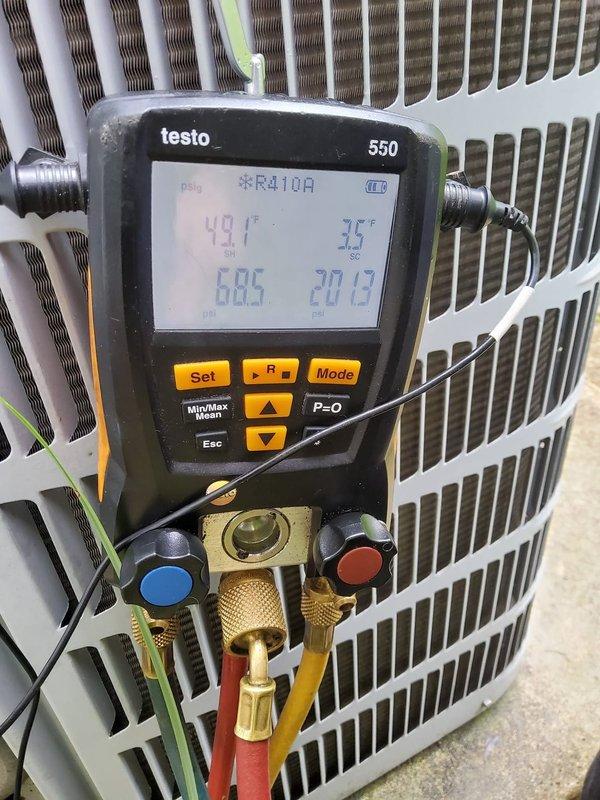 Responded to AC unit repair call and performed diagnostic evaluation of residential air conditioning system. Connected Testo 550 digital manifold gauge to outdoor condenser unit and measured refrigerant pressures and temperatures for R410A system. Recorded suction pressure of 20.19 psi with corresponding temperature of 35°F, and discharge pressure of 68.5 psi with temperature of 48°F. Inspected indoor furnace and air handler components in basement, verifying proper ductwork connections and system configuration. Documented system conditions with diagnostic photos for service records. Unit operational following assessment.