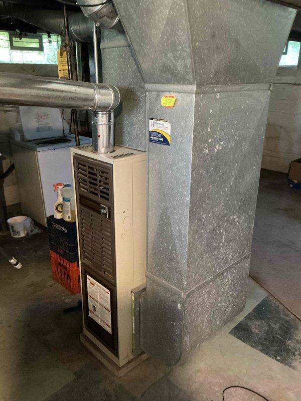 Conducted on-site evaluation of existing HVAC system in basement mechanical room for furnace and air conditioning replacement estimate. Assessed current beige furnace unit with exhaust venting, galvanized metal ductwork plenum, and overall system configuration including water heater proximity and available workspace. Documented equipment specifications, existing installation layout, and structural considerations through detailed photography to provide accurate replacement system recommendations and installation planning.