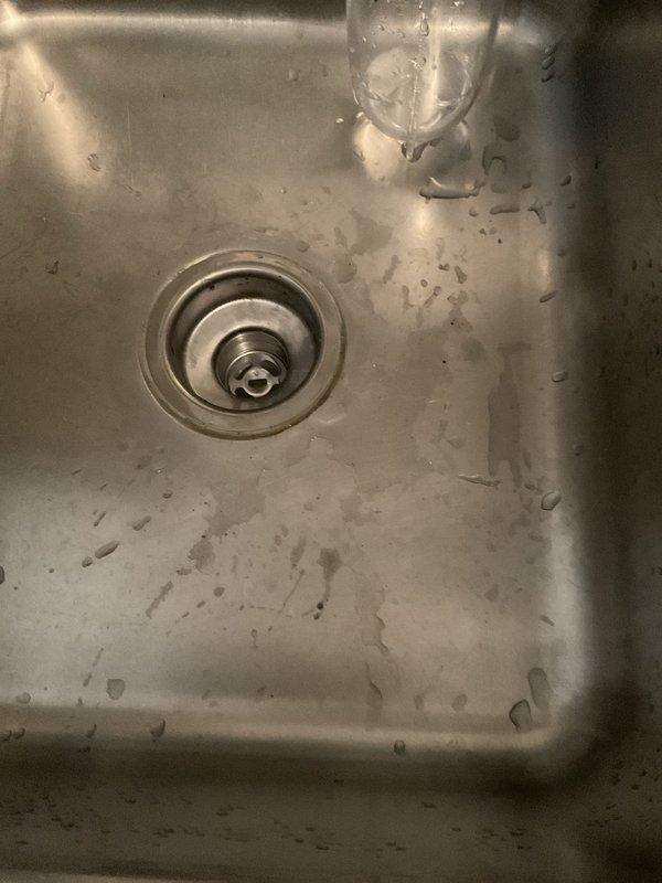Accessed kitchen sink plumbing through interior wall opening, requiring relocation of household items due to difficult access conditions. Installed new basket strainer assembly and connected to existing drain piping. Replaced tubular drain components under kitchen sink to restore proper drainage function. Inspected dripping kitchen sink and shower faucets as requested, with repairs pending customer approval.