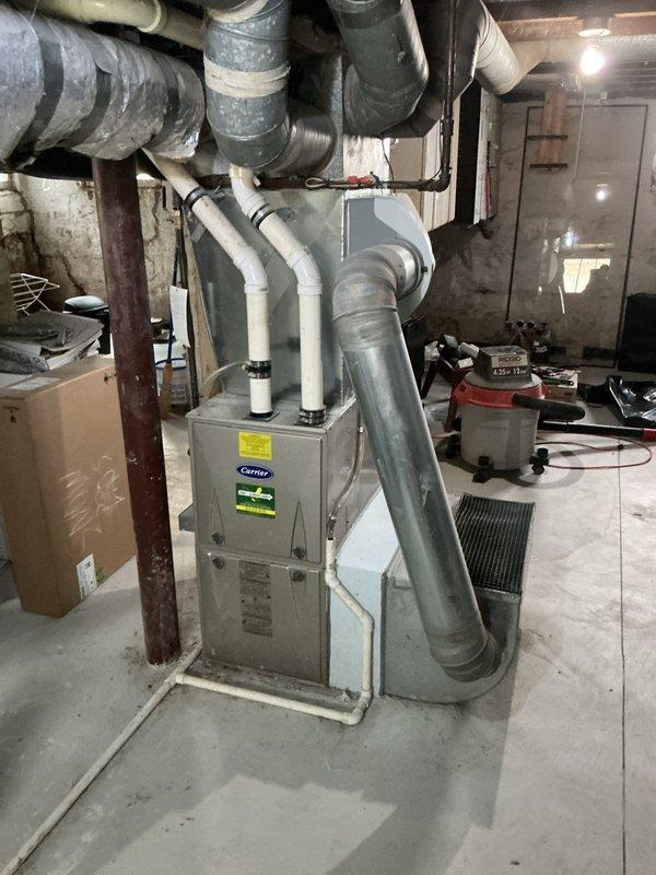 Completed installation of add-on air conditioning system to existing Carrier furnace in basement utility area. Integrated new AC components with existing ductwork infrastructure, installed necessary refrigerant lines, condensate drainage, and electrical connections to provide cooling capability while maintaining existing heating system functionality.