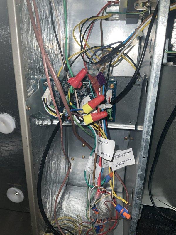 Responded to service call for second-floor air handler experiencing intermittent operation with startup noise but no fan or cooling function. Upon inspection, accessed control panel and identified wiring and control board issues preventing proper system operation. Examined circuit boards, wire connections, and control components within the air handler compartment. Verified proper wire terminations at connection points and inspected condition of control boards and associated wiring harnesses. Documented internal panel configuration and component layout showing multiple wire connections, circuit boards, and control relays. System evaluated for electrical continuity and proper control voltage at connection terminals.