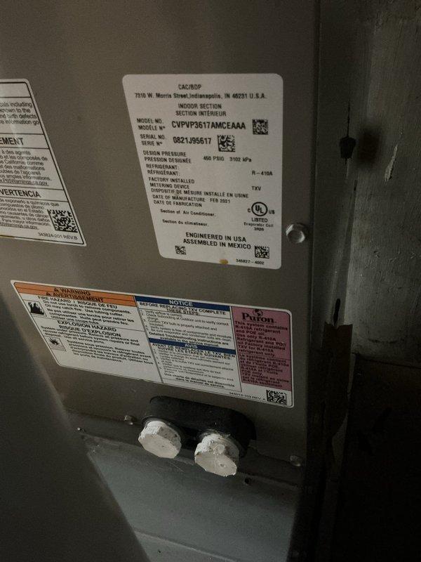 Responded to service call for ice buildup on refrigerant piping at a three-year-old Carrier air conditioning system. Connected Fieldpiece 3-port manifold gauges to measure system pressures and temperatures to diagnose the freezing condition. Based on gauge readings and visual inspection of the evaporator coil and suction line, determined the ice accumulation was likely caused by restricted airflow or low refrigerant charge, both common causes of evaporator coil freezing. Documented system conditions with photographs of the indoor air handler unit showing manufacturer specifications and diagnostic equipment in place during testing. System evaluation completed and findings communicated to address the freezing issue.