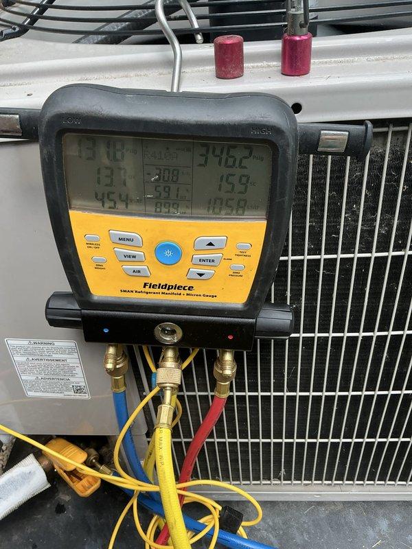 Responded to service call for ice buildup on refrigerant piping at a three-year-old Carrier air conditioning system. Connected Fieldpiece 3-port manifold gauges to measure system pressures and temperatures to diagnose the freezing condition. Based on gauge readings and visual inspection of the evaporator coil and suction line, determined the ice accumulation was likely caused by restricted airflow or low refrigerant charge, both common causes of evaporator coil freezing. Documented system conditions with photographs of the indoor air handler unit showing manufacturer specifications and diagnostic equipment in place during testing. System evaluation completed and findings communicated to address the freezing issue.