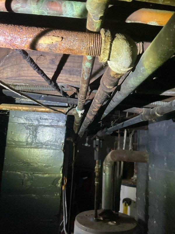 Responded to gas leak call at apartment unit 4. Upon arrival, inspected gas piping system in basement/crawlspace area and identified compromised section of gas line with hole requiring immediate repair. Located leak in heavily corroded steel gas pipe with significant rust deterioration throughout visible piping infrastructure. Documented existing conditions with photos showing extensive oxidation on threaded connections, unions, and pipe surfaces. Assessed structural environment including floor joists and surrounding utility systems. Identified safety hazard requiring prompt attention to restore gas service integrity and eliminate leak risk. Repair work needed on damaged section of gas line to address hole and restore safe operation of gas system.