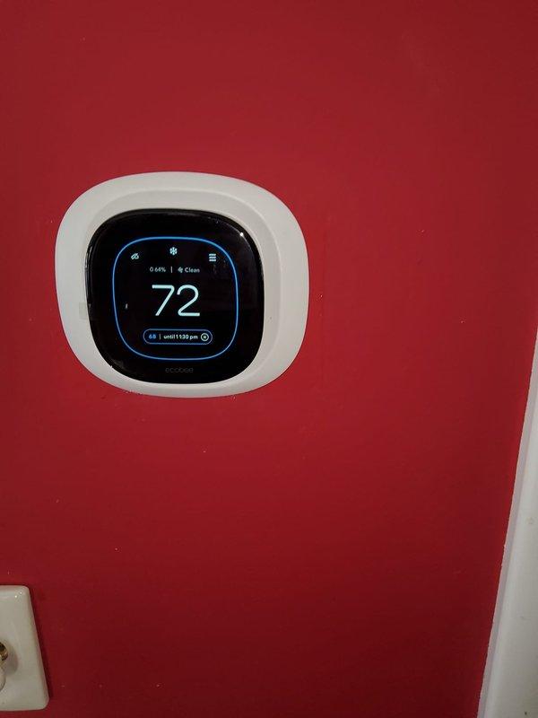 Completed Stage 2 of furnace installation in residential property with basement location. Installed new heating system and connected all ductwork to existing white cylindrical supply runs visible in ceiling area. Addressed structural concerns related to water-damaged wooden framing and deteriorated ceiling materials in work vicinity. Mounted and programmed new digital smart thermostat on main level wall, configured temperature settings to 72°F with scheduled programming to 68°F until 3:05 PM. Verified proper system operation, airflow through supply ducts, and thermostat communication with new furnace unit. Completed all electrical connections and tested heating cycle for proper ignition and temperature control functionality.