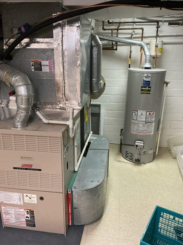Completed estimate for furnace replacement in basement mechanical room. Assessed existing beige Lennox furnace unit with connected ductwork and provided replacement recommendations for homeowner preparing property for sale. Documented current equipment configuration including metallic supply and return ductwork connections, flexible duct routing, and clearance specifications in utility space shared with water heating equipment.