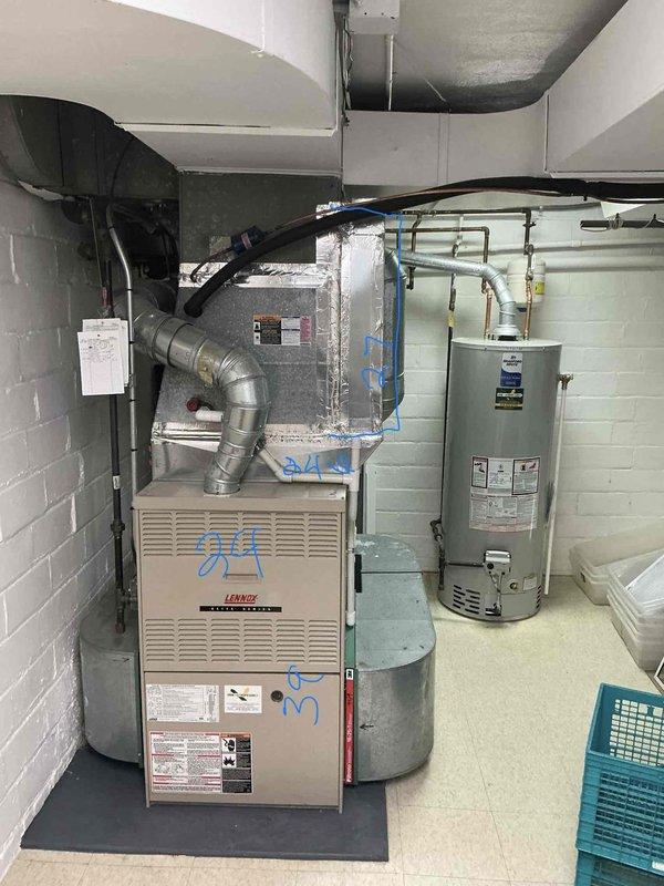 Completed estimate for furnace replacement in basement mechanical room. Assessed existing beige Lennox furnace unit with connected ductwork and provided replacement recommendations for homeowner preparing property for sale. Documented current equipment configuration including metallic supply and return ductwork connections, flexible duct routing, and clearance specifications in utility space shared with water heating equipment.