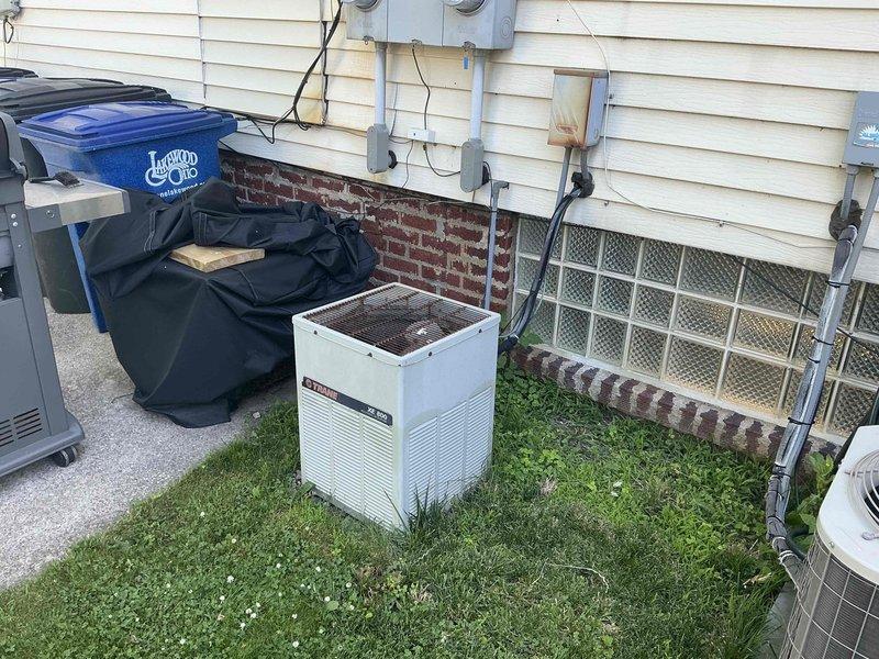 Replaced 1980s-era Trane air conditioning unit with seized compressor motor on one side of rental duplex property. Removed old outdoor condenser unit and installed new replacement system on existing concrete pad, connecting electrical conduit and refrigerant lines to interior air handler. System tested and confirmed operational upon completion of early morning installation.