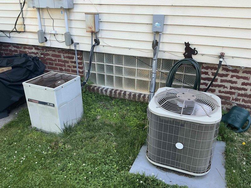 Replaced 1980s-era Trane air conditioning unit with seized compressor motor on one side of rental duplex property. Removed old outdoor condenser unit and installed new replacement system on existing concrete pad, connecting electrical conduit and refrigerant lines to interior air handler. System tested and confirmed operational upon completion of early morning installation.