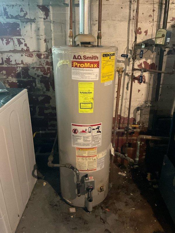 Responded to emergency call for failed 24-year-old A.O. Smith ProMax water heater that was actively leaking and had flooded the basement. Upon arrival, assessed the extent of water damage and confirmed the unit had reached end of service life with catastrophic tank failure. Shut off water supply and drained remaining water from the failed unit. Disconnected all copper supply and discharge piping, removed old water heater from basement utility room, and disposed of failed equipment. Installed new replacement tanked water heater with proper connections to existing copper plumbing infrastructure, including hot and cold water lines and temperature/pressure relief valve discharge piping. Verified all connections for proper sealing, restored water supply, filled tank, and tested unit operation to ensure proper heating function and no leaks. System returned to full operational status with no further water intrusion.