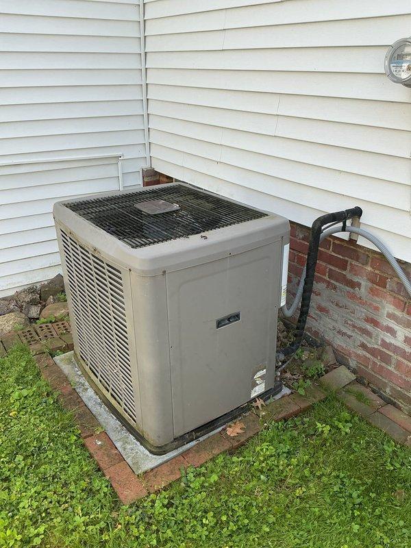 Responded to service call for 16-year-old central air conditioning system experiencing reduced cooling capacity and increased blower noise. Inspected outdoor condenser unit and indoor air handler, documented equipment condition with photographs showing weathered exterior components and refrigerant line routing. System unable to maintain temperature below 74 degrees, requiring diagnostic evaluation of compressor performance, refrigerant charge levels, and blower motor operation to determine necessary repairs.
