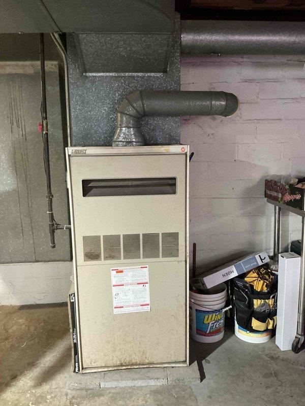 Conducted on-site evaluation of existing 1983 gas furnace system and assessed property for complete HVAC system replacement including addition of central air conditioning. Inspected existing furnace unit located in basement utility area, documented current equipment specifications, ductwork configuration, and electrical connections. Evaluated existing duct system capacity and routing to determine compatibility with proposed air conditioning installation. Photographed equipment nameplate data, furnace condition, surrounding workspace clearances, and overhead duct runs to prepare comprehensive replacement estimate for gas furnace and new AC system.