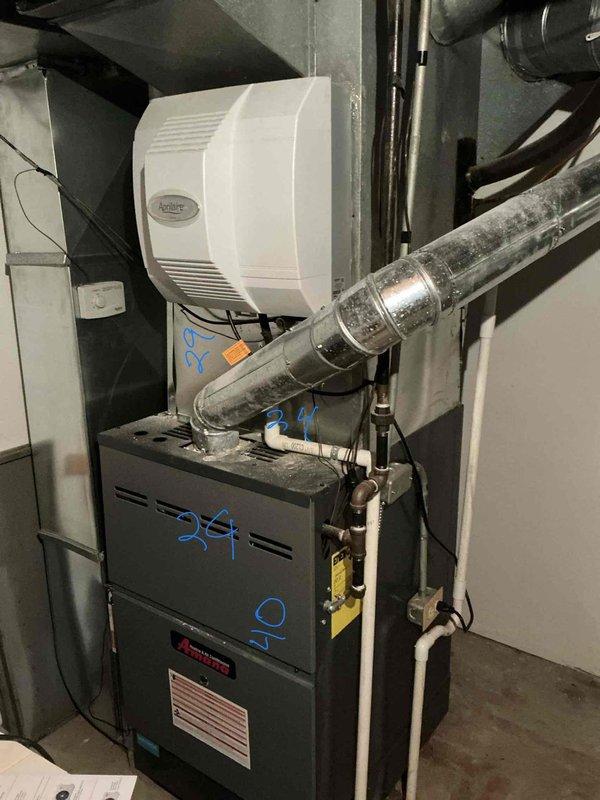 Responded to service call for non-functional air conditioning system affecting entire residence. Upon arrival, evaluated 40-year-old outdoor AC unit that had reached end of serviceable life. Conducted comprehensive system assessment including inspection of existing furnace, ductwork, and associated HVAC components in mechanical room. Documented current equipment configuration including furnace unit with connected humidifier, metallic ductwork with visible age-related wear and dust accumulation, and existing copper refrigerant lines. Photographed installation showing gray metal heating equipment, black insulated refrigerant lines with flexible connections, brass valve fittings, and silver metallic duct system. Prepared detailed estimate for complete air conditioning system replacement given the advanced age of equipment and failure to operate, recommending modern energy-efficient replacement unit to restore cooling functionality to the home.