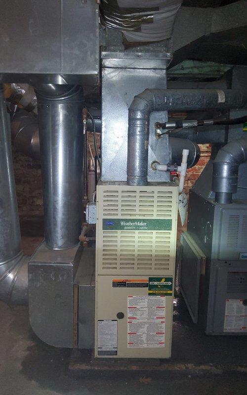 Responded to no cooling complaint affecting entire residence with 26-year-old home and aging HVAC system. Upon arrival, inspected outdoor condensing unit which exhibited significant rust deterioration on top panel and fan grill assembly, indicating unit was likely original equipment and well beyond expected service life. Evaluated indoor Carrier WeatherMaker furnace and associated ductwork in basement mechanical room, confirming system configuration and verifying air handler operation. Documented equipment condition showing extensive weathering and corrosion on outdoor unit components. Advised customer that aging air conditioning system requires replacement due to deteriorated condition and age-related failure, as unit has exceeded manufacturer's expected lifespan and repair would not be cost-effective given the extent of component degradation observed.