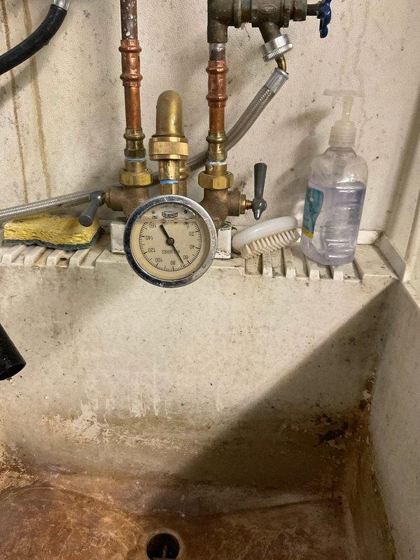 Responded to service call for malfunctioning valve causing restricted water flow and retrieved quick-connect hose left behind from previous AC service. Conducted thorough inspection of plumbing system including utility sink area and exterior hose bib assembly. Evaluated pressure gauge readings at both interior copper pipe manifold and outdoor spigot to diagnose flow restriction issue. Inspected valve operation, brass fittings, and connection points for potential blockages or mechanical failure. Documented existing conditions including pressure measurements and valve functionality through photographic evidence for service records.