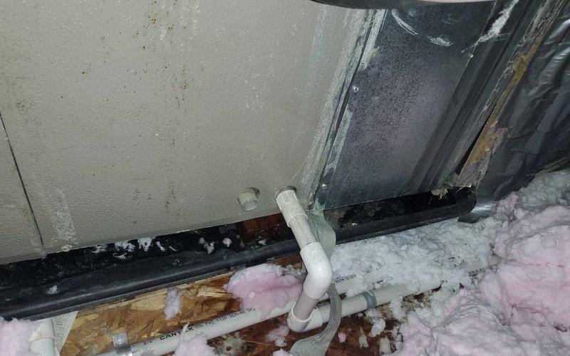 # HVAC Service Report: Water Leak Investigation and Resolution

Responded to service call for air conditioning unit experiencing water leakage. Unit was installed in 2019, with outdoor condenser approximately 7 years old. 

Upon arrival, conducted comprehensive system inspection to identify source of reported leak. Investigation revealed multiple contributing factors affecting system performance and moisture management.

Basement/crawl space inspection identified PVC condensate drain line configuration near foundation wall. Observed water staining and discoloration on floor surfaces indicating historical moisture intrusion. Pink fiberglass insulation showed signs of moisture exposure. Condensate drainage system components were examined for proper pitch, clogs, and functional operation.

Attic inspection revealed critical findings related to ductwork and moisture issues. Located flexible supply duct with extensive frost and ice accumulation along its surface, indicating severe temperatu