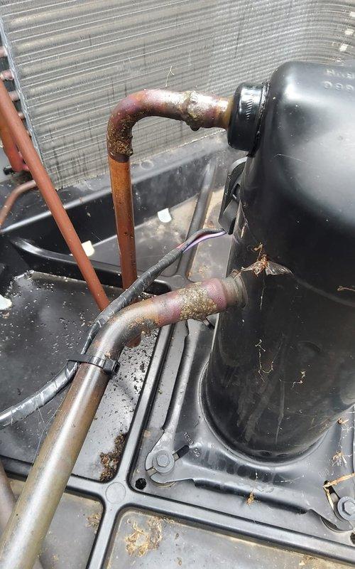 Responded to service call for refrigerant leak on rooftop condensing unit, model RA1636AJ1NA. Upon inspection, identified active leak at compressor oil port and observed significant corrosion on copper refrigerant lines and fittings. Documented equipment condition with photos showing weathered piping, oxidation on copper connections, and compromised components requiring immediate attention to prevent further refrigerant loss and system failure.