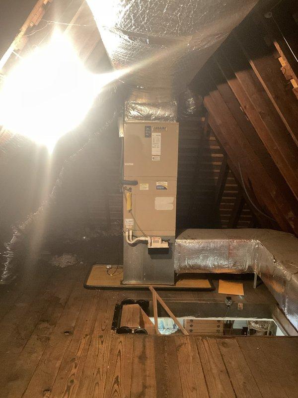 Responded to service call for non-operational air conditioning system affecting residential cooling. Upon arrival, confirmed the outdoor condenser unit had ceased functioning and was approximately 20 years old, well beyond its typical service life. Customer indicated a previous repair had been attempted and requested an evaluation for complete system replacement. Performed visual inspection of the outdoor condenser unit positioned against the exterior brick wall, noting the age and condition of the equipment. Examined the indoor air handler unit located in the attic space, observing the existing ductwork configuration and installation. Documented system components with photographs for replacement estimate preparation. Provided professional assessment and recommendations for new equipment installation based on the failed condenser and advanced age of the current system.