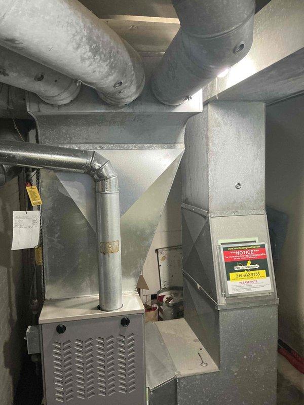 Conducted comprehensive on-site evaluation for add-on air conditioning system installation to existing forced-air heating infrastructure. Assessed current ductwork configuration, plenum connections, and available space in mechanical room to determine optimal placement and integration points for new cooling equipment. Documented existing furnace/air handler setup, including cabinet-style unit with decorative grille, supply and return duct pathways, and insulated ductwork runs to facilitate proper AC coil installation and refrigerant line routing for seamless system integration.