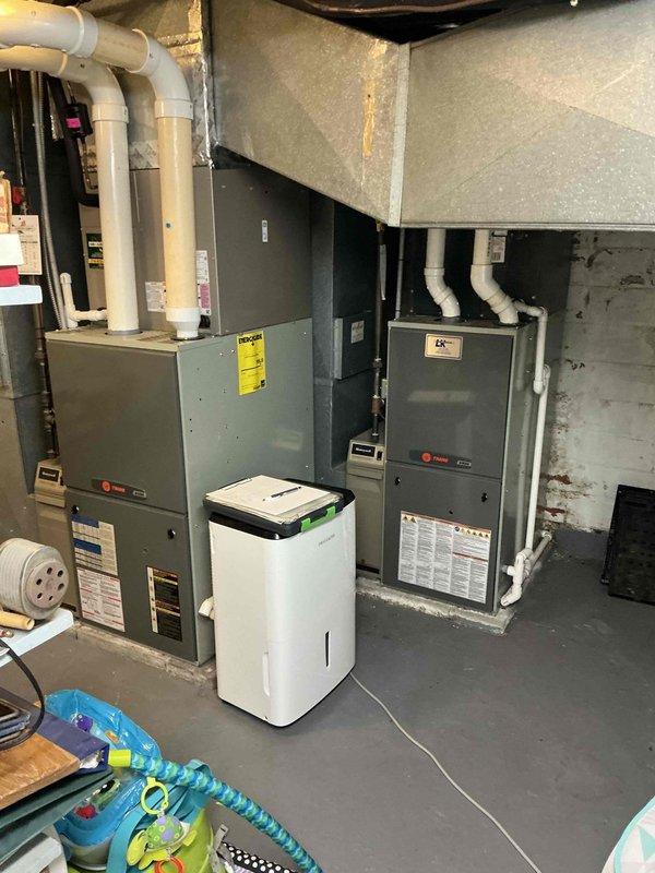 Conducted estimate for 20-year-old air conditioning system experiencing no cooling to third floor. Inspected basement mechanical room containing dual furnace units with associated ductwork, PVC condensate lines, and existing HVAC infrastructure. Evaluated outdoor condenser unit location in courtyard area. Provided replacement options for aging system to restore proper cooling capacity throughout multi-level residence.