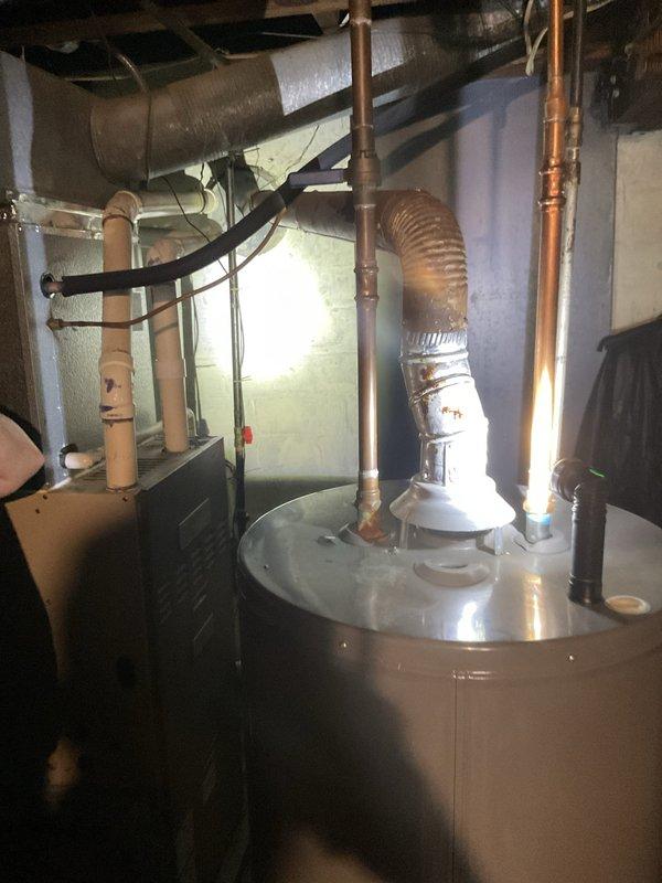 Responded to follow-up service call for tanked water heater that experienced loss of hot water after previous repair completed on 4/27. Upon arrival, performed comprehensive inspection of water heater system, including all copper supply lines, gas connections, venting assembly, electrical components, and associated plumbing infrastructure. Documented current condition of equipment with photographs showing water heater installation with proper venting through corrugated metal exhaust duct, multiple copper pipe connections at varying diameters, and black rubber connector hoses. Assessed entire mechanical system including overhead ductwork, PVC piping, and utility room configuration to identify root cause of recurring hot water failure.