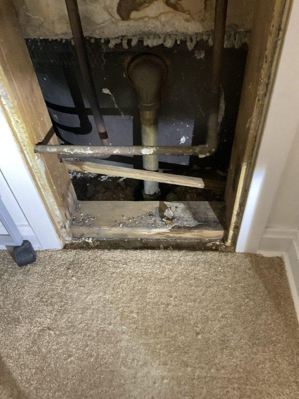 Responded to tub drain issue at 90-year-old residential building, apartment F109. Upon investigation, accessed plumbing system through wall cavity behind closet area, revealing aged brass/copper drain fittings and horizontal support piping. Assessed drainage components within wall structure to diagnose and address the reported bathtub drain concern.