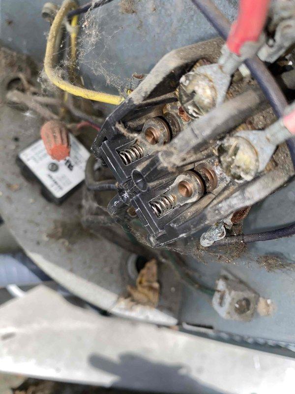 # HVAC Service Report

Responded to emergency no-cooling call on residential air conditioning system. Upon arrival, performed system diagnostic and visual inspection of outdoor condensing unit. Found compressor contactor assembly in severely deteriorated condition with extensive corrosion, dirt accumulation, and oxidation on electrical terminals and connections. White corrosion buildup was prominent around terminal screws and mounting hardware, indicating prolonged moisture exposure and environmental contamination. Multiple wire connections showed signs of compromised integrity due to corrosion at contact points.

Documented equipment condition with photographs showing the extent of deterioration on electrical components. The contactor assembly exhibited heavy rust on metal surfaces and significant debris accumulation that could impair electrical connectivity and system operation. Advised customer of findings and recommended replacement of corroded contactor assembly to restore proper 