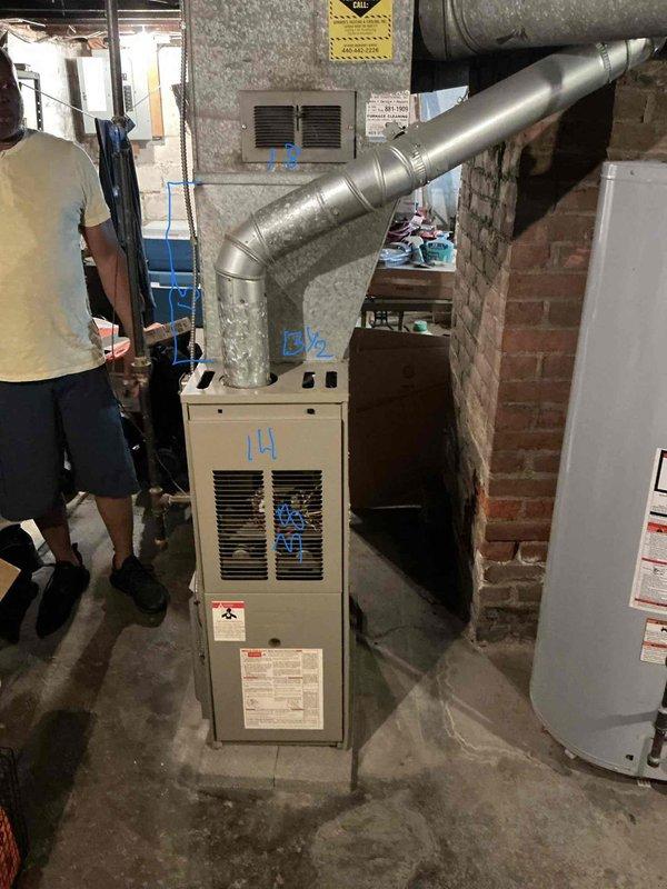 Completed on-site assessment for furnace and air conditioning system replacement in residential basement utility area. Evaluated existing beige furnace unit with overhead ductwork configuration, documented current equipment specifications and installation layout, and captured detailed photographs of mechanical room conditions including ductwork routing, available clearances, and existing infrastructure to prepare comprehensive replacement estimate for new HVAC system installation.