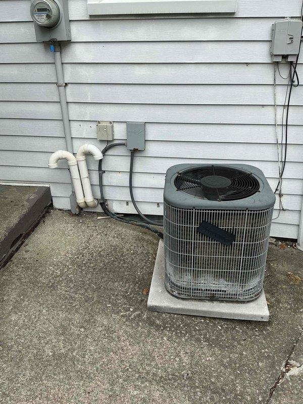 Responded to emergency service call for non-cooling air conditioning system with unknown equipment age. Upon inspection of the basement mechanical area and exterior condenser unit, documented existing HVAC system configuration including furnace, outdoor condensing unit, associated refrigerant lines, electrical disconnect, and condensate drainage system. Assessed overall system condition, noting aged equipment and installation characteristics. Provided comprehensive estimate for complete HVAC system replacement to restore cooling functionality and improve system efficiency.