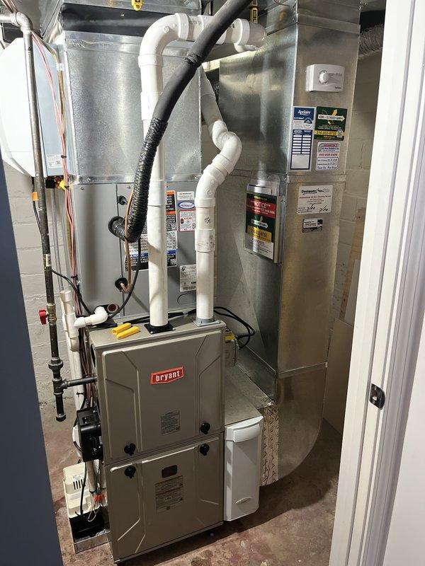 Completed full HVAC system replacement including removal of existing equipment and installation of new Bryant heat pump system with matching furnace and evaporator coil. Installed Ecobee smart thermostat for enhanced climate control and integrated 700CFM fresh air ventilation system. Outdoor heat pump unit mounted on composite pad with proper gravel base and electrical disconnect, while indoor components including furnace and air handler positioned in basement utility area with all refrigerant lines, condensate drainage, and PVC venting properly routed and secured per manufacturer specifications.
