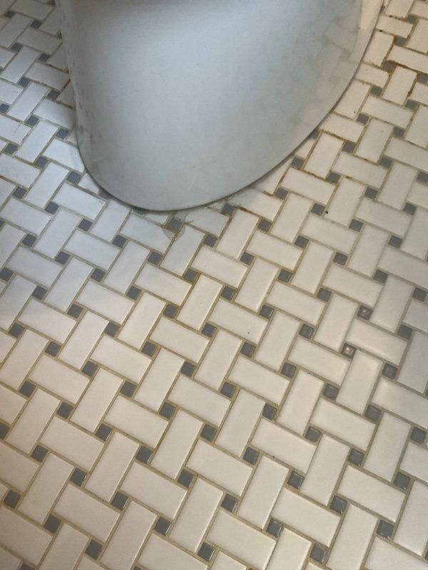 Responded to service call for leaking toilet in 1950s-era home. Upon inspection, identified water seepage at base of toilet fixture where it meets the basketweave-pattern tile floor. Removed and reset toilet, replaced deteriorated wax ring seal, and tightened closet bolts to manufacturer specifications. Verified proper seating of fixture on floor flange, tested for leaks by flushing multiple times, and confirmed no water discharge at base. System returned to normal operation with no further leakage detected.