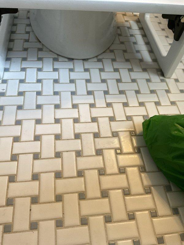 Responded to service call for leaking toilet in 1950s-era home. Upon inspection, identified water seepage at base of toilet fixture where it meets the basketweave-pattern tile floor. Removed and reset toilet, replaced deteriorated wax ring seal, and tightened closet bolts to manufacturer specifications. Verified proper seating of fixture on floor flange, tested for leaks by flushing multiple times, and confirmed no water discharge at base. System returned to normal operation with no further leakage detected.