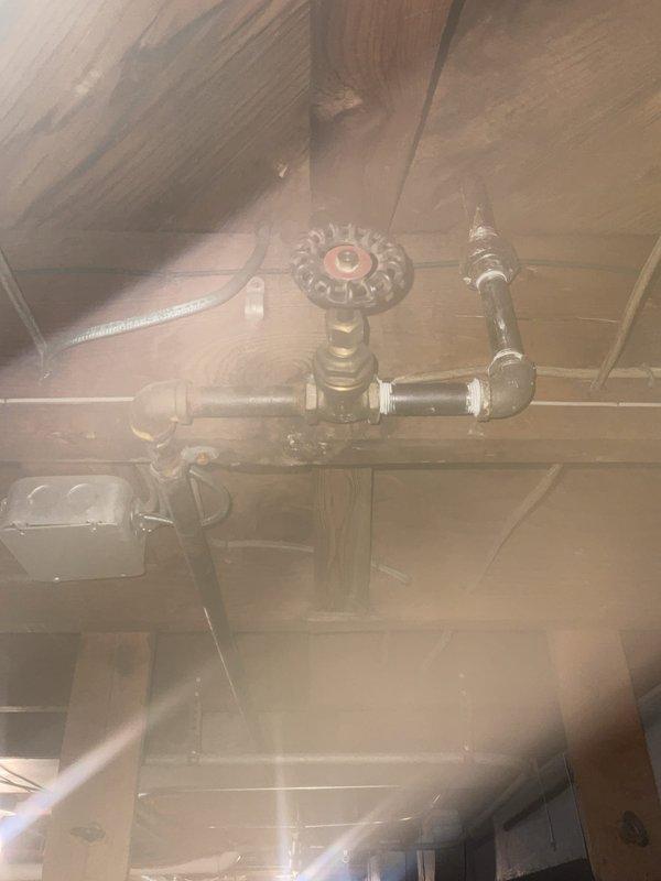 Performed routine maintenance flush on tanked water heater in 71-year-old residential property. Unit was operating properly at time of service. Accessed water heater system in basement utility area with exposed plumbing infrastructure and aging brass valve assemblies. Completed standard flush procedure to remove sediment buildup and maintain optimal heater performance. Inspected visible plumbing connections, including oxidized copper piping and vintage brass valves with cross-handles showing age-appropriate patina. All components functioned as expected during maintenance procedure. System returned to normal operation upon completion.