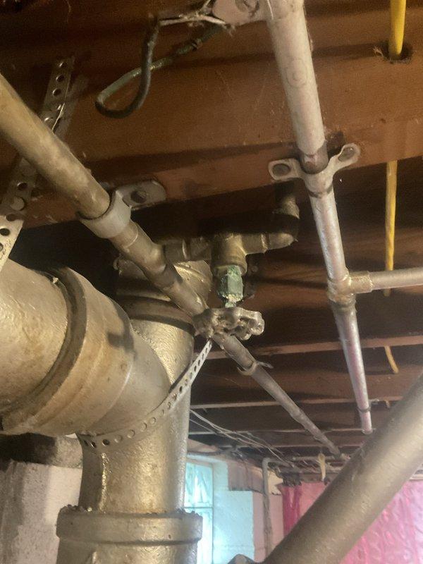 Performed routine maintenance flush on tanked water heater in 71-year-old residential property. Unit was operating properly at time of service. Accessed water heater system in basement utility area with exposed plumbing infrastructure and aging brass valve assemblies. Completed standard flush procedure to remove sediment buildup and maintain optimal heater performance. Inspected visible plumbing connections, including oxidized copper piping and vintage brass valves with cross-handles showing age-appropriate patina. All components functioned as expected during maintenance procedure. System returned to normal operation upon completion.